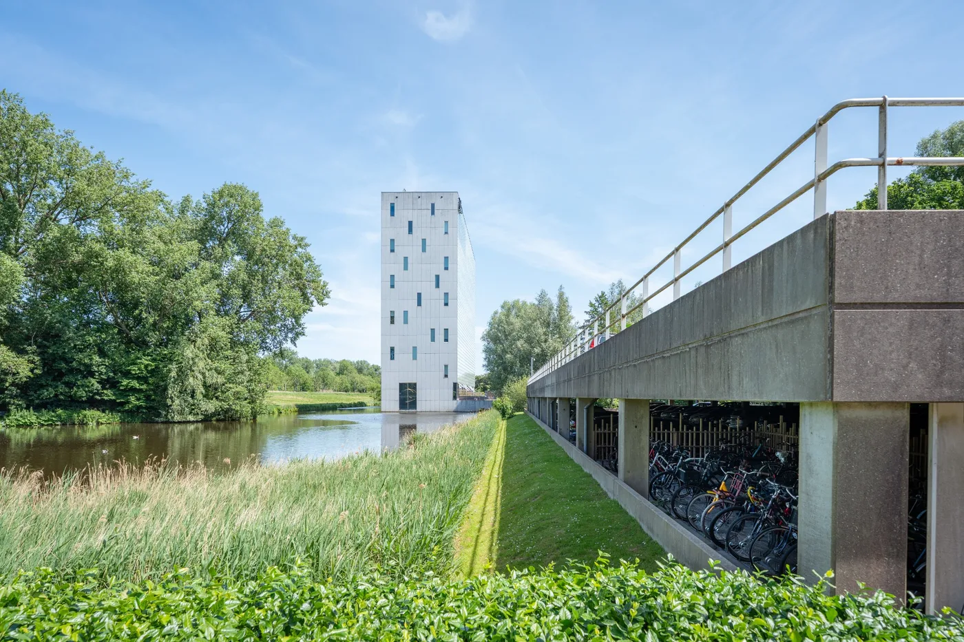 Groene omgeving bij Nest Werkplekken in Amstelveen met water, bomen en een overdekte fietsenstalling